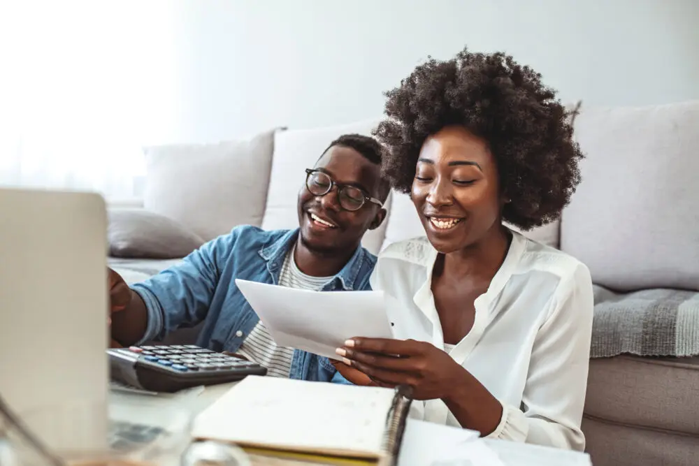 black couple smiling while managing bills