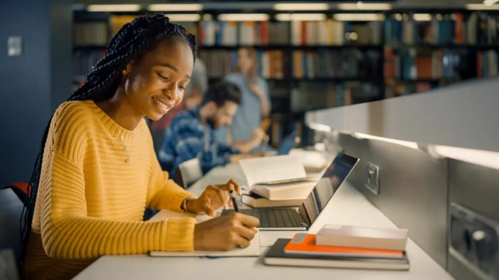 Black student working on laptop at the library