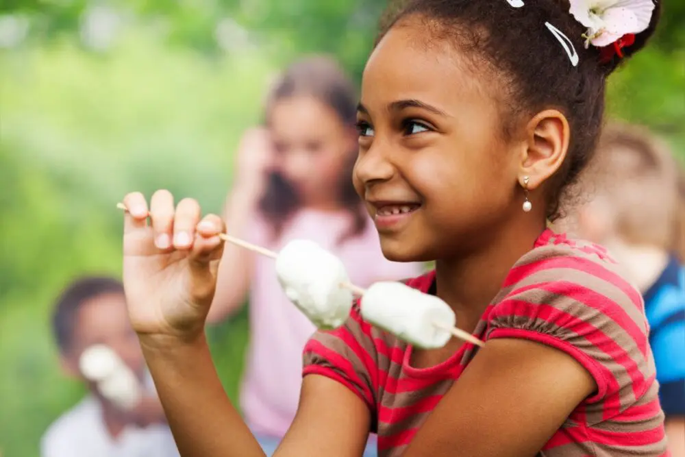 Black girl child at a summer camp with marshmallows