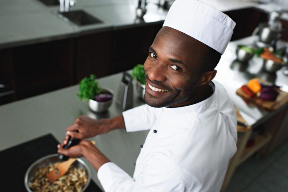 smiling cook seasoning food | black-owned catering & african american chefs